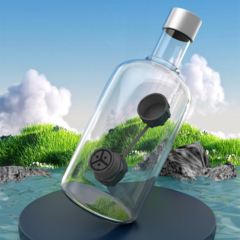 Clear bottle with black cap on a grassy and water background