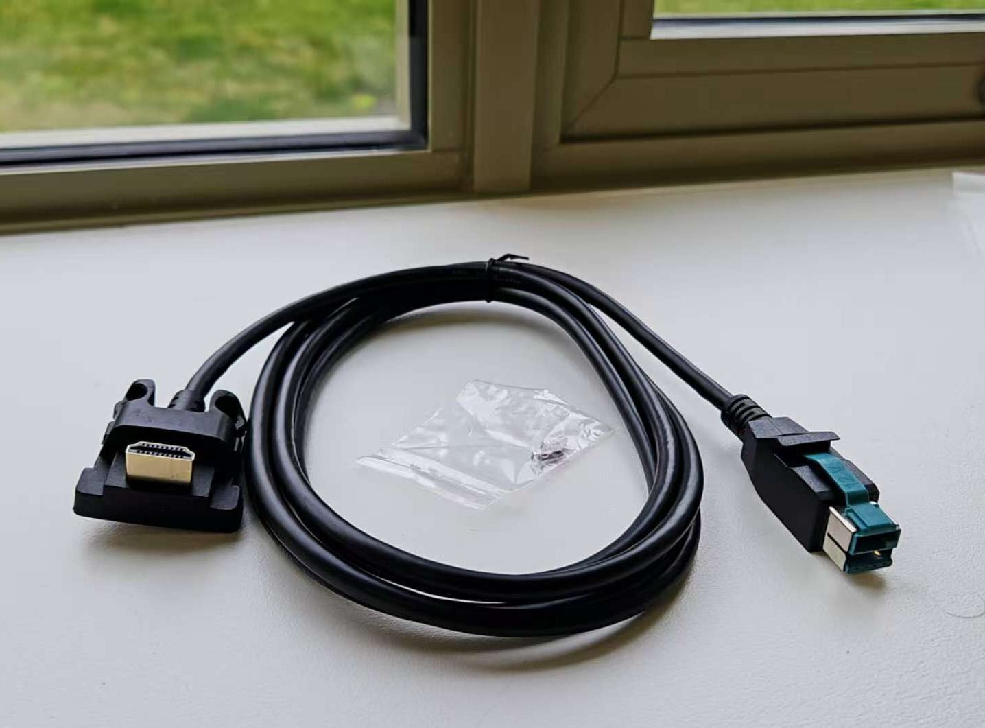 Black cable with USB connectors on a light surface near a window