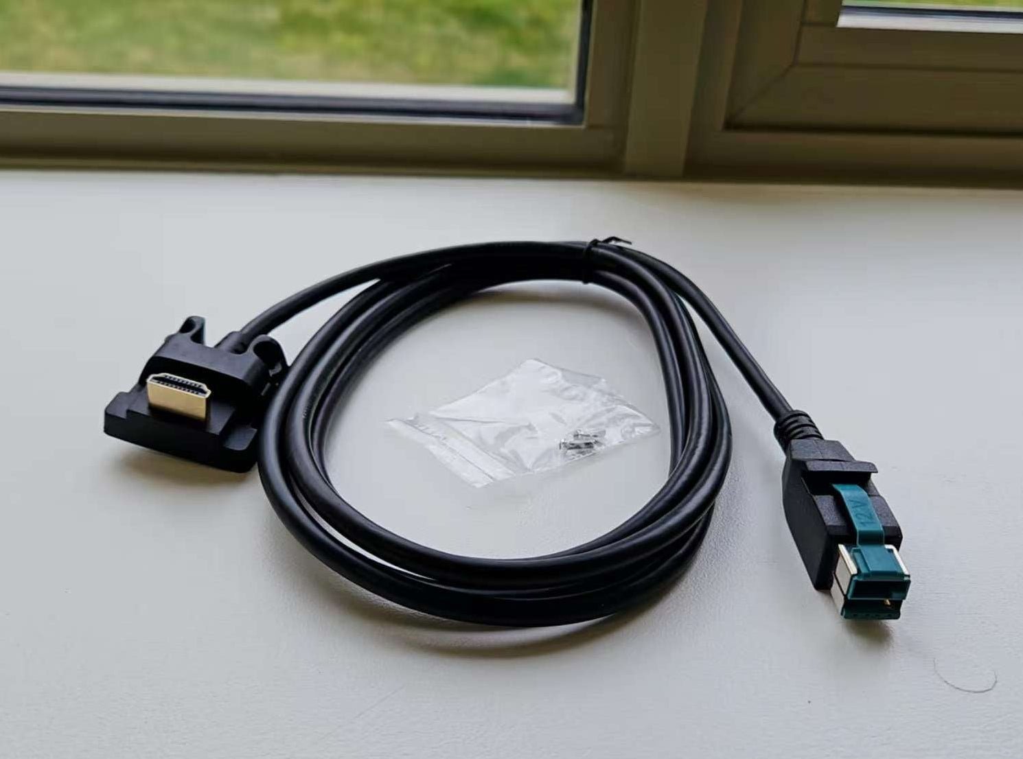 Black cable with connectors on a light surface near a window