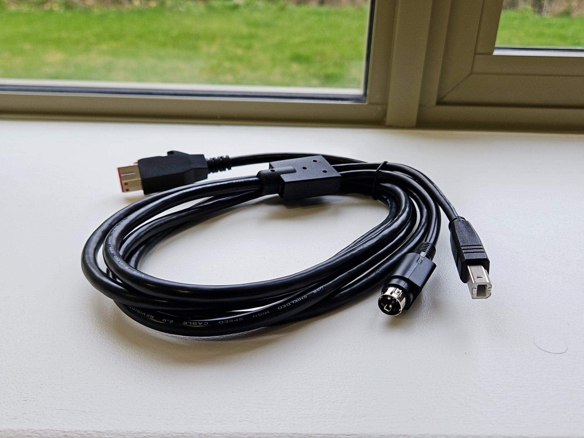 Black USB extension cable on a white surface with a window in the background